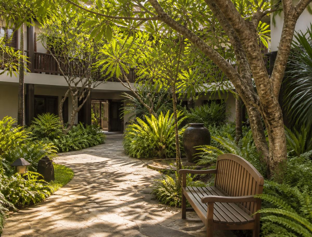 The private garden courtyard at Hota Grand with stone path and teak bench